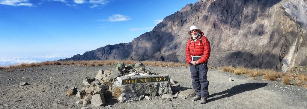 Person standing at Hindu Point 3300 summit with rocky terrain and mountains in the background.