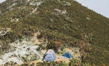 Two camping tents set up on the slopes of Mount Hanang surrounded by greenery.