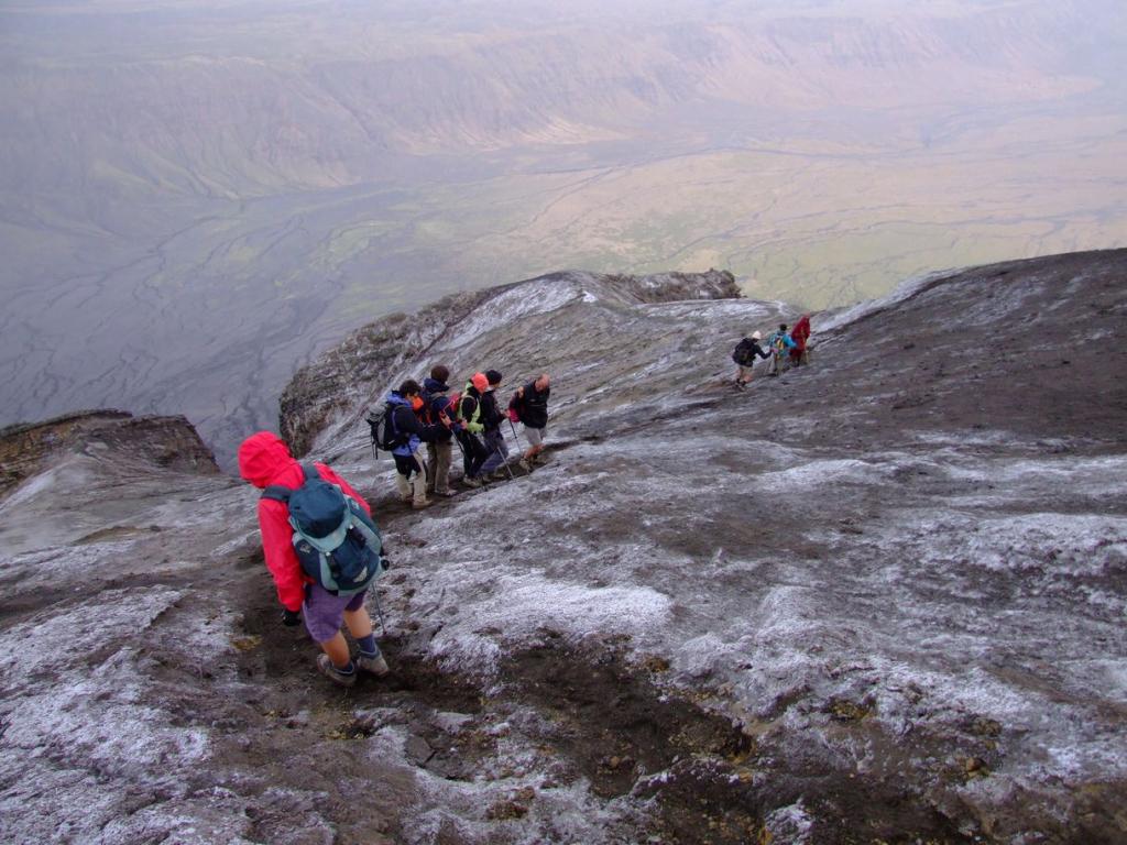 Group of hikers climbing the Ol Doinyo Lengai volcano in Tanzania, with a rugged landscape in the background.